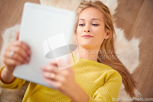 Image of Her E-book was getting intense. A young woman lying on the floor reading a book on her digital tablet.