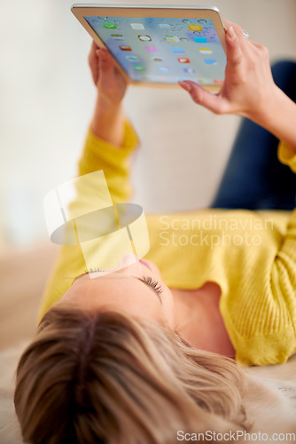 Image of What have we got here. A young woman lying on the floor using a digital tablet.