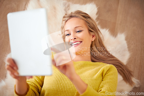 Image of Over a thousand friend requests. A young woman lying on the floor holding her digital tablet.