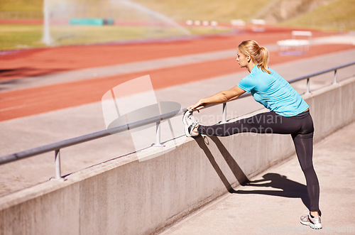 Image of Ready for a race. an attractive young runner stretching out on the track.