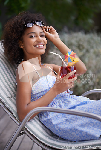 Image of Living life to the max. an attractive ethnic woman holding up her sunglasses with a cocktail outdoors.