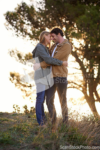 Image of A romantic escape. A happy couple standing affectionately outdoors while the sun rises.