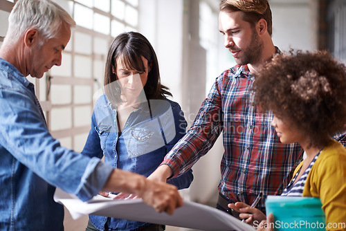 Image of Coming up with great strategies. A group of colleagues standing in a buliding assessing a blueprint.