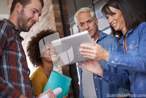 Image of All in for a successful project. A group of colleagues standing around a digital tablet to assess building plans.