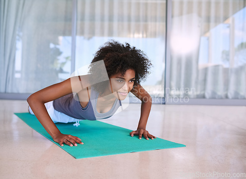 Image of Getting stronger with each rep. an attractive young woman doing push-ups on an exercise mat.