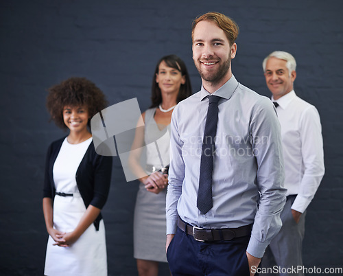 Image of In pursuit of success. a young professional man standing in front of a group of coworkers.