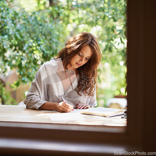 Image of The sun is her inspiration. an attractive young woman writing in a relaxed environment outdoors.
