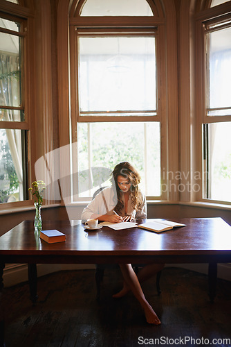 Image of Shes hard at work on a new novel. an attractive young woman writing in a relaxed environment at home.