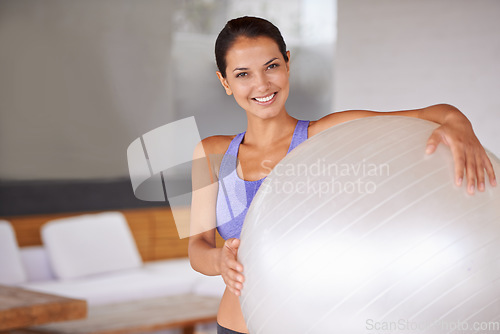 Image of Ready for some ball work. Portrait of a beautiful young woman holding an exercise ball at home.