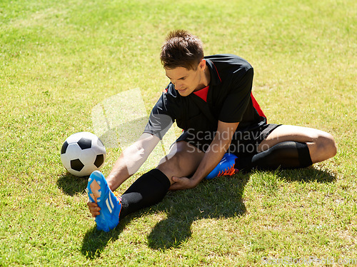 Image of Stretching before the match. a young footballer stretching on the field.
