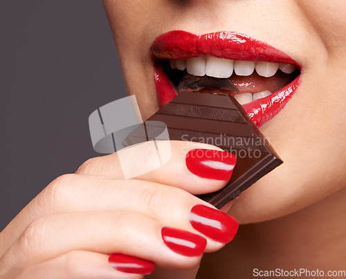 Image of Every woman needs a guilt-free chocolate day. Closeup portrait of a cute young female biting on a chocolate bar.