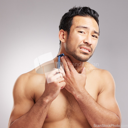 Image of Handsome young mixed race man shirtless in studio isolated against a grey background. Hispanic male in pain after cutting himself while shaving. Take care when you groom or shave your beard and face