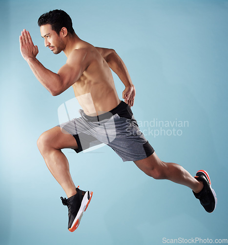 Image of Fullbody young hispanic man running in studio isolated against a blue background. Mixed race shirtless male athlete running or sprinting to win a race. Endurance training to increase his cardio