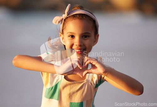 Image of Shell make you believe in magic again. an adorable little girrl showing a heart shale with her fingers at the beach.