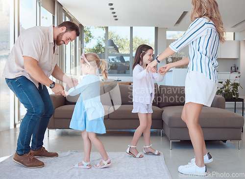 Image of Caucasian family of four having fun and dancing together in the living room at home. Happy little playful girls bonding with mom and dad. Carefree loving parents entertaining their energetic daughter