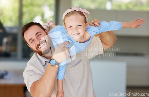 Image of Adorable little girl pretending to fly while being lifted by dad. Father playing with his adorable daughter at home