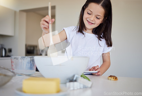 Image of Happy little girl baking at home. Smart girl mixing ingredients to prepare dough in the kitchen. Helpful child in the kitchen