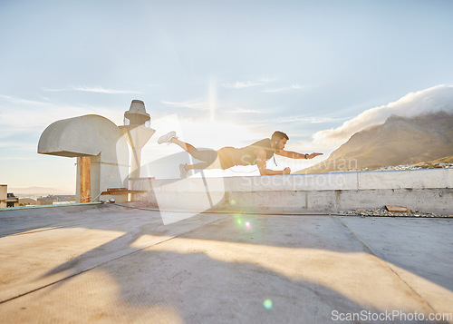Image of It time for you discover just how capable you are. a man doing a single-arm plank while on a rooftop.