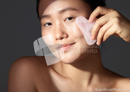 Image of You dont need go out to get spa results. Studio shot of a beautiful young woman using a scraping tool on her face.