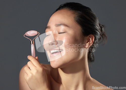 Image of People always ask about my skincare. Studio shot of a beautiful young woman holding a face roller.