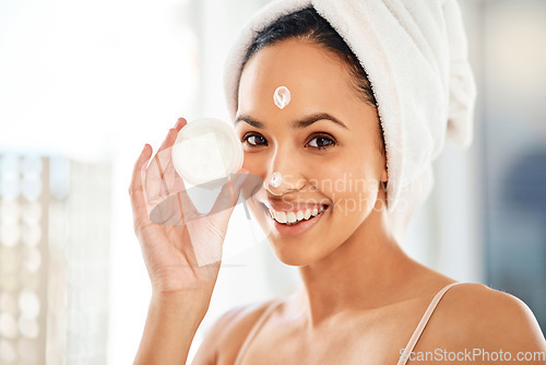 Image of Revealing my beauty secrets. a young woman applying cream to her face at home.
