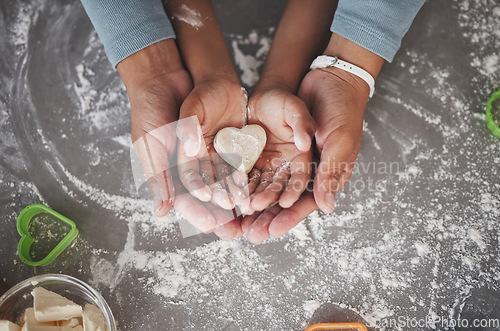 Image of Cookies are made of butter and love. an unrecognizable girl and her mom holding a heart shaped cookie in the kitchen at home.