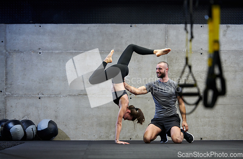 Image of A muscular man assisting a fit woman in a modern gym as they engage in various body exercises and muscle stretches, showcasing their dedication to fitness and benefiting from teamwork and support