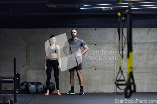 Image of Muscular man and fit woman in a conversation before commencing their training session in a modern gym.