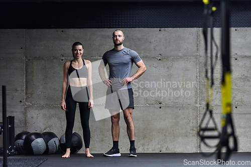Image of Muscular man and fit woman in a conversation before commencing their training session in a modern gym.