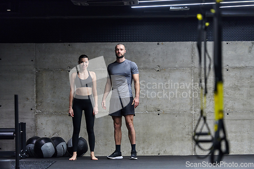 Image of Muscular man and fit woman in a conversation before commencing their training session in a modern gym.