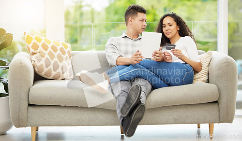 Image of What do you think. a couple using a digital tablet and credit card on the sofa at home.