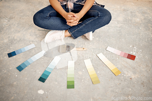 Image of Can you help me decide on a colour. an unrecognizable woman sitting on the ground with a paintbrush and colour swatches.