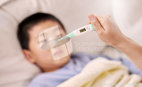 Image of Looks like your temperature is a little high. a woman checking her sons temperature with a thermometer.
