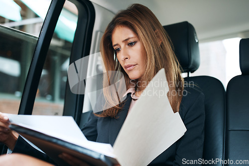 Image of Who said work only happens in an office. a mature businesswoman going through paperwork in the back seat of a car.