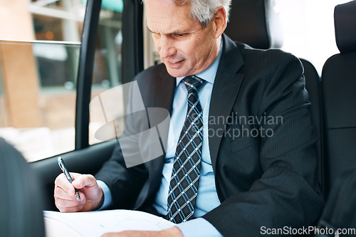 Image of Places to go and contracts to sign. a mature businessman going through paperwork in the back seat of a car.