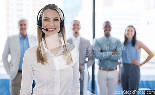 Image of Lets make life a lot easier for you. Portrait of a mature businesswoman using a headset in a modern office with her team in the background.