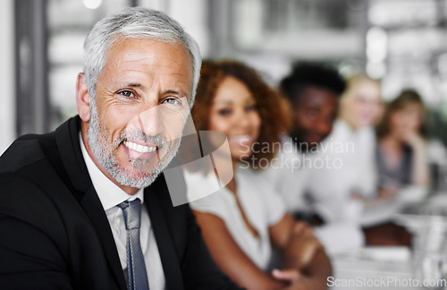 Image of I love meetings, they are so informative. Portrait of a businessman sitting in a boardroom meeting with colleagues blurred in the background.