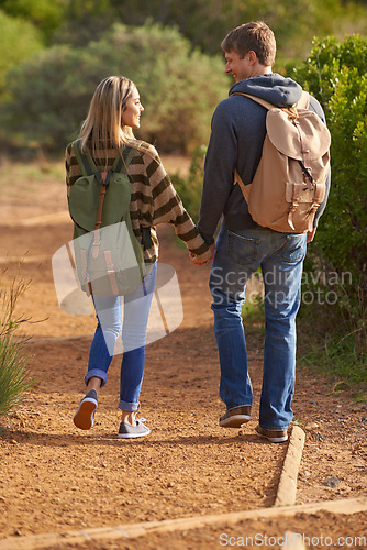 Image of On the trail of love. Rear view shot of a young couple holding hands and walking down a hiking trail.