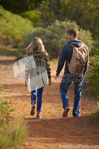 Image of The walk of love. Rear view shot of a young couple walking down a hiking trail.