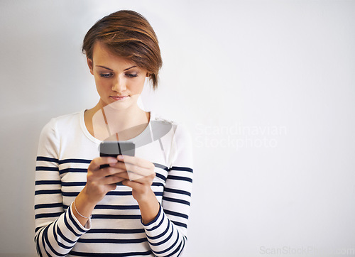 Image of Lost in mobile conversation. A cropped shot of a beautiful young woman using a smartphone.