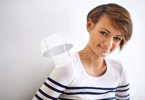 Image of Young, beautiful and carefree. A cropped portrait of a beautiful young woman standing against a white wall.