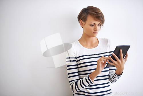 Image of Staying connected. A cropped portrait of a beautiful young woman holding a tablet.