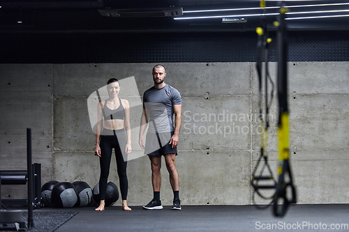 Image of Muscular man and fit woman in a conversation before commencing their training session in a modern gym.