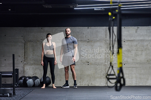 Image of Muscular man and fit woman in a conversation before commencing their training session in a modern gym.