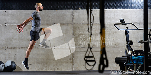 Image of A muscular man captured in air as he jumps in a modern gym, showcasing his athleticism, power, and determination through a highintensity fitness routine