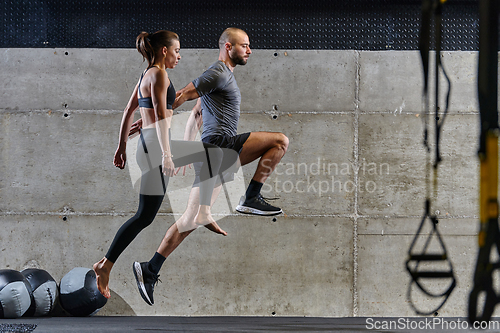 Image of A fit couple exercising various types of jumps in a modern gym, demonstrating their physical fitness, strength, and athletic performance