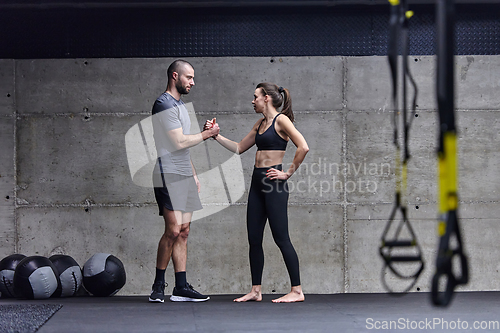 Image of Muscular man and fit woman in a conversation before commencing their training session in a modern gym.