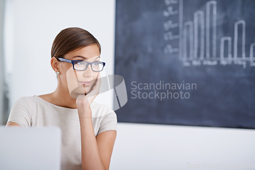 Image of Lost in thought on a busy day. Portrait of a young business woman sitting at a desk.