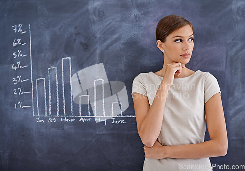 Image of The business could be doing better. an attractive business woman beside a blackboard.