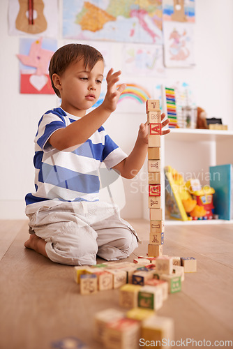 Image of Hes an avid little builder. a cute little boy boy playing with building blocks in his room.